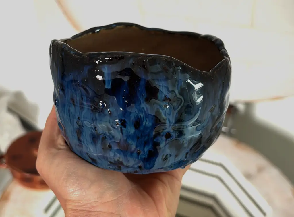 imagem de uma peça esmaltada de cerÂmica, a peça possui tons azulados e pretos