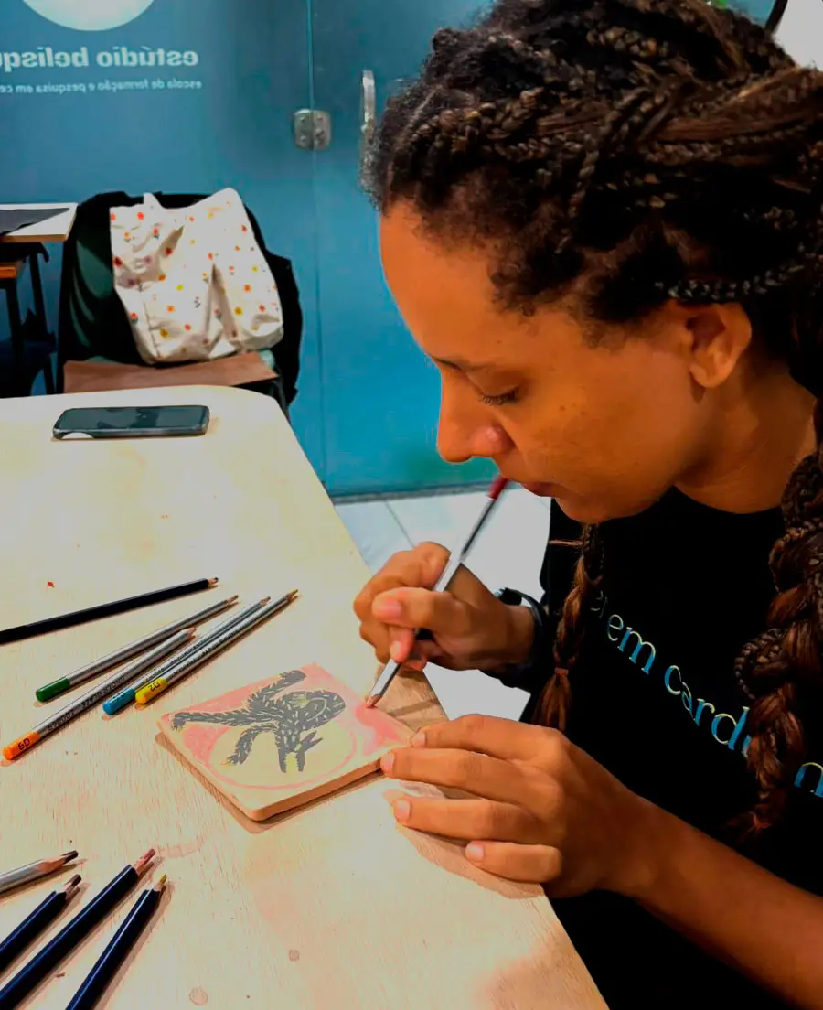 imagem de uma mulher desenhando com l&aacute;pis em pe&ccedil;as de cer&Acirc;mica